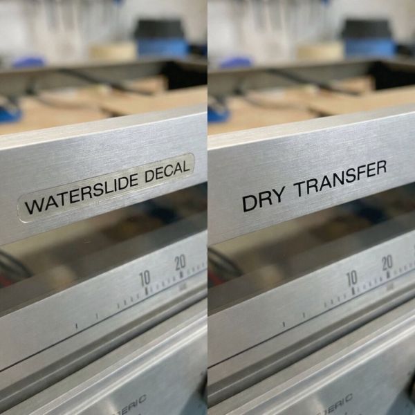 A side-by-side comparison showing the visible carrier film halo of a waterslide decal versus the seamless, painted-on appearance of a dry transfer on a brushed aluminum faceplate.