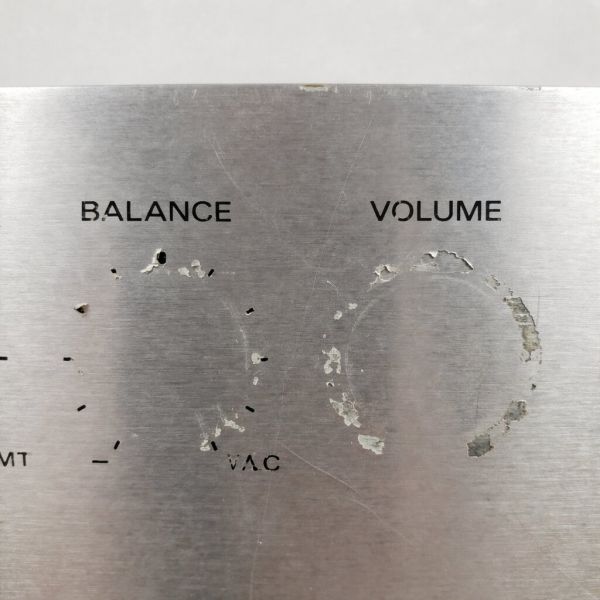 A close-up of a vintage audio faceplate with flaking and worn silk-screened lettering around the 